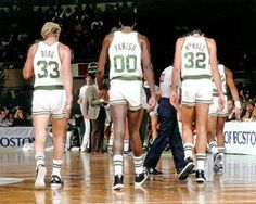 three basketball players walking on the court with their numbers printed on them and two men in white shorts