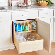 an open drawer in the middle of a kitchen with dishes and utensils inside