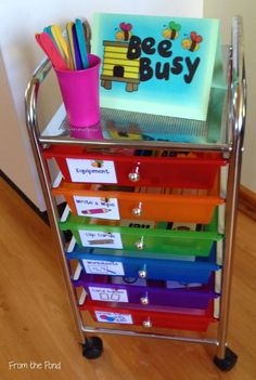 a metal cart filled with lots of different colored folders and pens on top of a hard wood floor