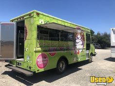 a green food truck parked in a parking lot with its door open to the side