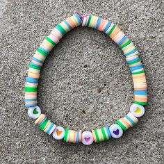 a bracelet made out of glass beads on the ground, with hearts and dots in different colors