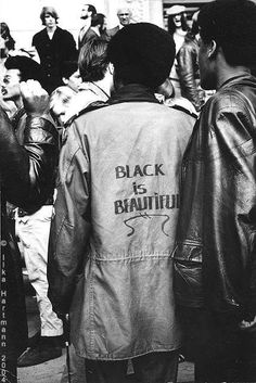 black is beautiful jacket on back of man standing in front of group of other people