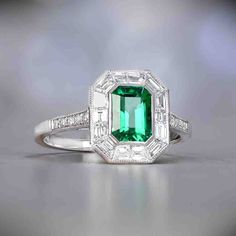 an emerald and diamond ring on a table