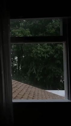 an open window in a dark room with trees outside