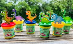 there are many toy dinosaurs in cups on the table