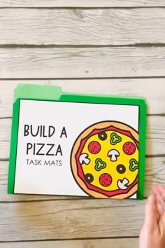 the build a pizza task mat is being held up by someone's hand