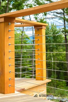 a wooden deck with metal railings and trees in the background