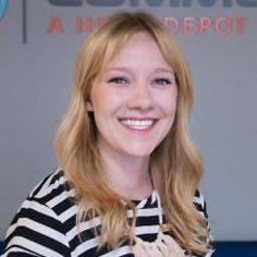 a woman with blonde hair is smiling for the camera while wearing a striped shirt and jeans