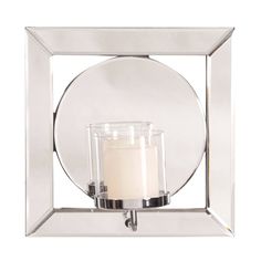 a glass candle holder with a white candle in it's center and a circular mirror behind it