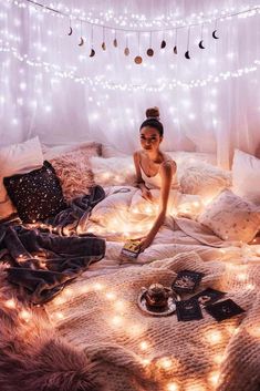 a woman sitting on top of a bed covered in lights