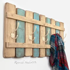 a coat rack made out of pallet wood with hooks on it and a scarf hanging from the wall