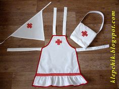 an apron and hat are laid out on the floor next to each other, including one with red crosses