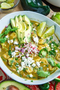 a white bowl filled with soup next to sliced avocado and cilantro