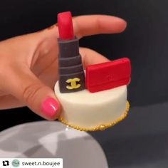 a woman's hand holding a miniature chanel lipstick holder