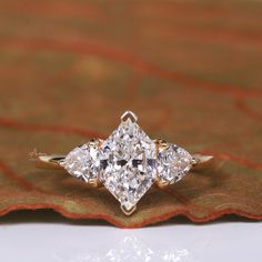 three stone diamond ring sitting on top of a leaf