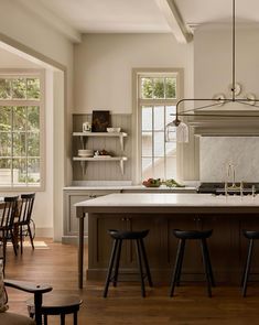 a kitchen with an island and stools in front of the counter top, along with two windows