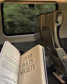 an open book sitting on top of a chair next to a window with the words dead port's society