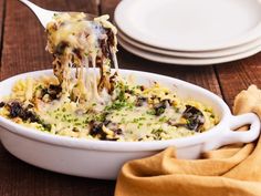 a white bowl filled with pasta covered in cheese and toppings on top of a wooden table