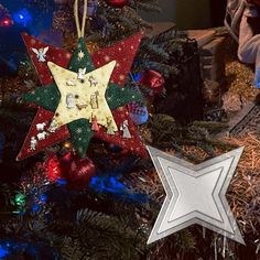 a star ornament hanging from the top of a christmas tree