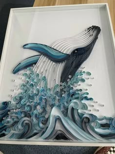 a glass artwork depicting a whale jumping out of the water in blue and white waves