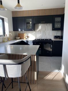 a modern kitchen with black cabinets and white counter tops, along with bar stools