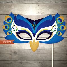 a blue mask with peacock feathers on top of a toothpick stick in front of a white wall