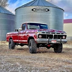 a red truck parked in front of a silo