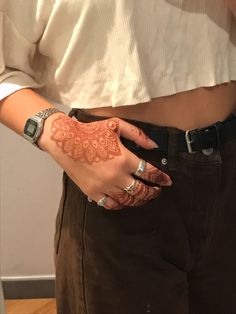 a woman with henna on her hand and wrist is standing in front of a mirror