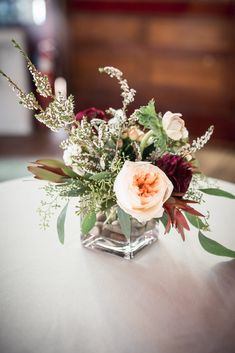 a vase filled with flowers sitting on top of a white table covered in greenery