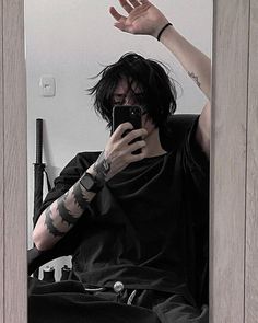 a man with tattoos on his arm taking a selfie in front of a mirror