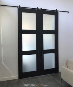 a white couch sitting next to a black sliding door in a living room on top of a hard wood floor