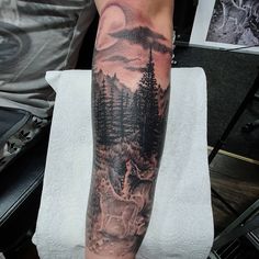 a man's arm with a forest scene on it