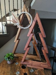 a wooden christmas tree sitting on top of a table next to a potted plant