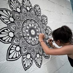 a woman is painting a flower on the wall