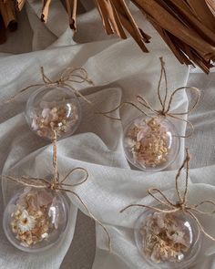 three clear glass ornaments tied with twine on top of a white cloth covered table