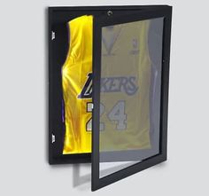 a basketball jersey hanging on the side of a wall in a black frame with yellow lining