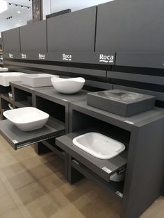 a row of sinks with bowls on them in a room filled with cabinets and counter tops