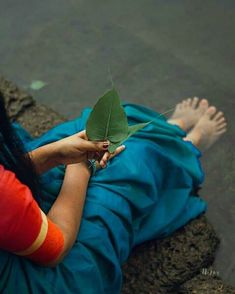 a woman laying on the ground holding a leaf