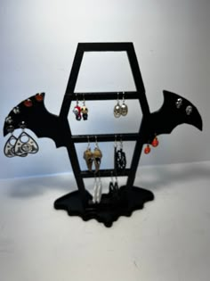 "3D Printed Coffin Shaped Earring Holder with Bat Wings. Holds   - 18 Pairs of Drop Style Earrings  - 30 Pairs of Post Style Earrings Bottom Base has a Reservoir for any extra small items you need to keep from being lost. Stand Measures: 12 1/2\" Tall x 13 1/2\" Wide x 4 3/4\" Deep Disclaimer The 3D printing process is not perfect so there may be blemishes in the surface finishes and visible layer lines. Some items may not be exactly as pictured and as much as we try to take accurate photos, the color may be slightly different than viewed on your screen. We do our best to make sure all 3d prints are free from blemishes, however there may be some slight imperfections from the 3d printing process. Sometimes the printing may leave a slightly layered surface and is custom to each individual pa Gothic Cricut Projects, 3d Printed Necklace Holder, 3d Printed Gothic, Goth Earring Holder, Gothic Halloween Plug Earrings, Bat Hoop Earrings, Gothic Earrings, Goth Home, Goth Decor