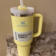 a yellow travel mug with a straw sticking out of it's lid sitting on a marble counter