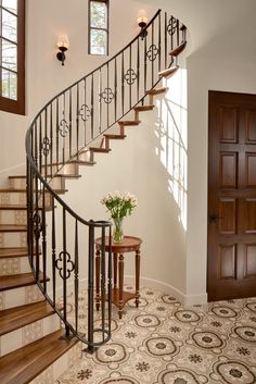 a spiral staircase with wrought iron railing and wooden handrails in a home entryway