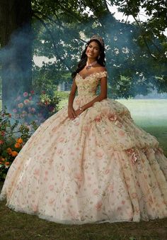 Embrace your inner fairytale princess with this whimsical Vizcaya quinceaera ball gown (style 89457). The delicately draped bodice features classic off-the-shoulder sleeves accented by stunning crystal beaded, three-dimensional flowers that add a touch of whimsy. The real magic lies in the skirt, crafted with a stunning combination of floral printed tulle layered over luxurious sparkle tulle. This creates a dimensional effect that shimmers with every move. Pickups in the skirt create a cascading waterfall look, further adding to the whimsical feel. Three-dimensional flowers are scattered throughout the skirt, echoing the details on the bodice and tying the whole look together. To complete your regal presence, a matching stole is included. This dress is sure to make you feel like a quinceae Allure Couture, Quince Dress, Sherri Hill Prom Dresses, Theme Dress, Mori Lee, Corset Bodice, Sherri Hill Dresses, Allure Bridal