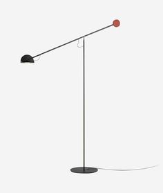 a black floor lamp with a red light on it's side and a white wall in the background