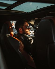 a man sitting in the driver's seat of a car looking out the window