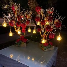 some red roses are sitting on top of a table with candles and lights around them