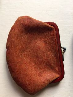 an old brown purse sitting on top of a white table next to a pair of scissors