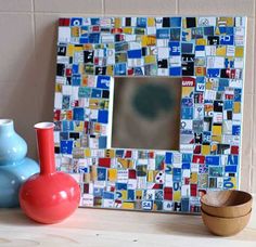 a mirror and vases sit on a table next to a wall with a mosaic design