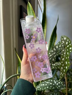 a person holding up a water bottle with flowers on the inside and in the outside