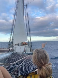 two people sitting on the back of a boat in the ocean pointing at something off to the side