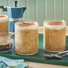 three glasses filled with pudding sitting on top of a table next to a coffee maker